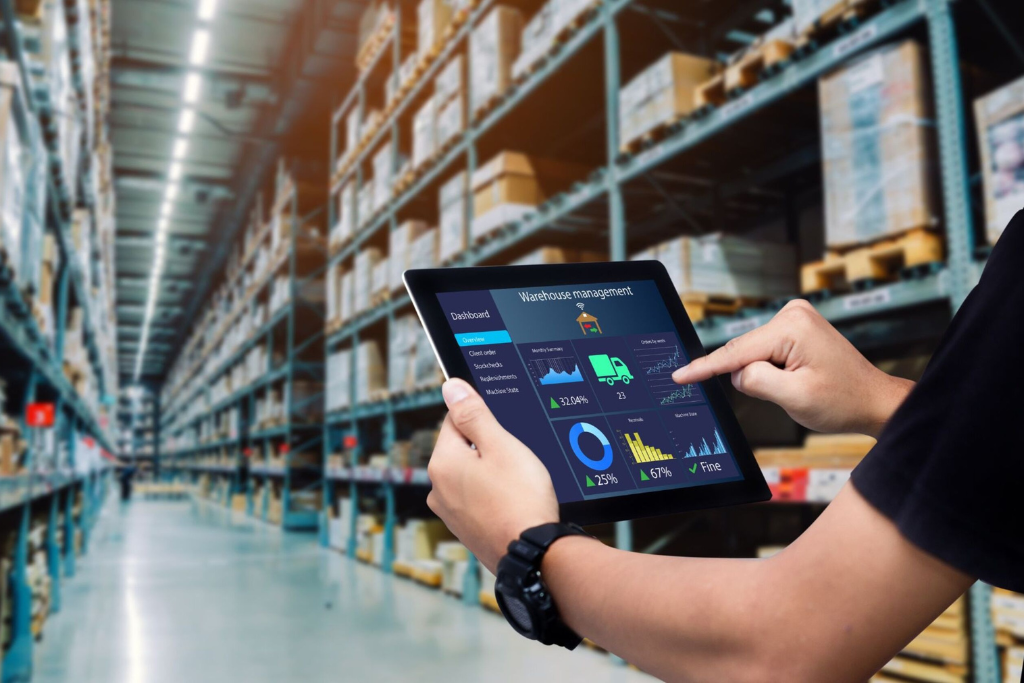 Person using a digital tablet to manage warehouse inventory and logistics in a large storage facility.